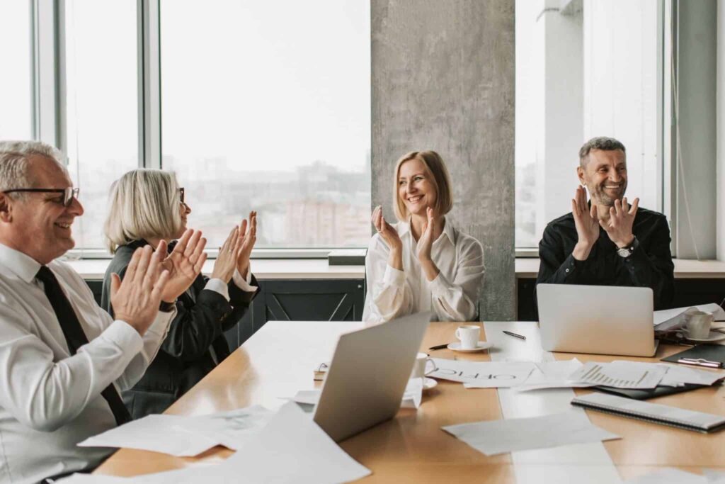 Cropped image of 2 men and 2 women sitting in boardroom of the office clapping after completing peri and menopause online training